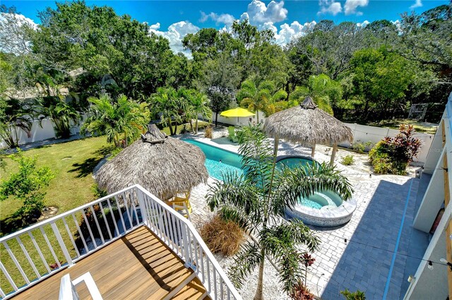 view of pool featuring a wooden deck, an in ground hot tub, and a yard