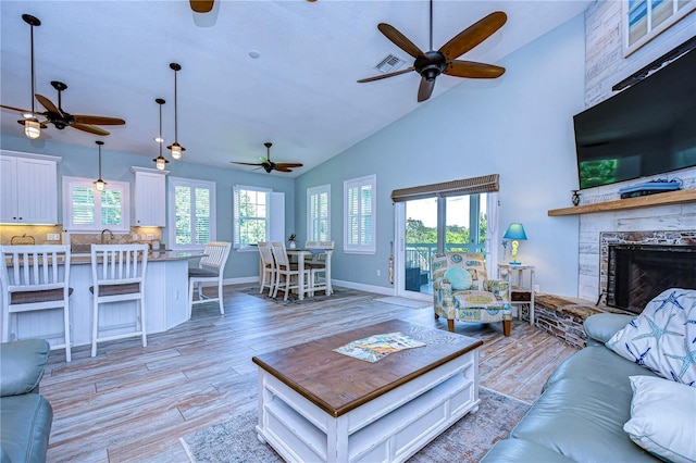 living room featuring light hardwood / wood-style floors, sink, a fireplace, and high vaulted ceiling