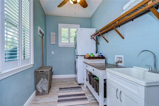 clothes washing area with ceiling fan, sink, light hardwood / wood-style flooring, and stacked washer and clothes dryer