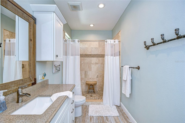 bathroom with hardwood / wood-style floors, vanity, toilet, and walk in shower