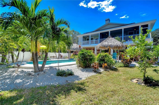 rear view of property with a fenced in pool and a yard