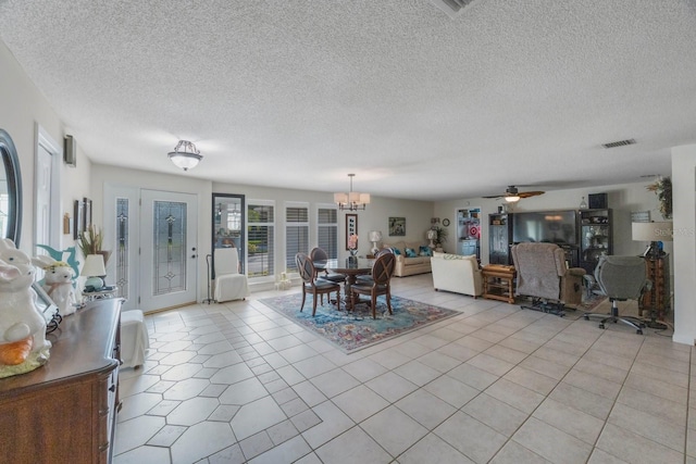 tiled dining space with a textured ceiling and ceiling fan with notable chandelier