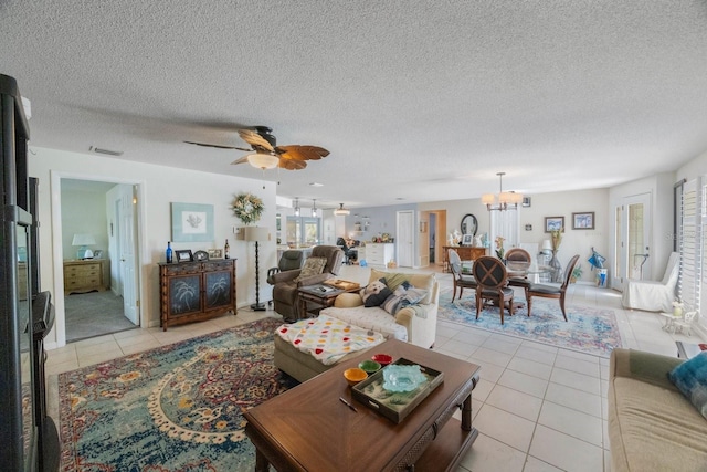 tiled living room with a textured ceiling and ceiling fan with notable chandelier