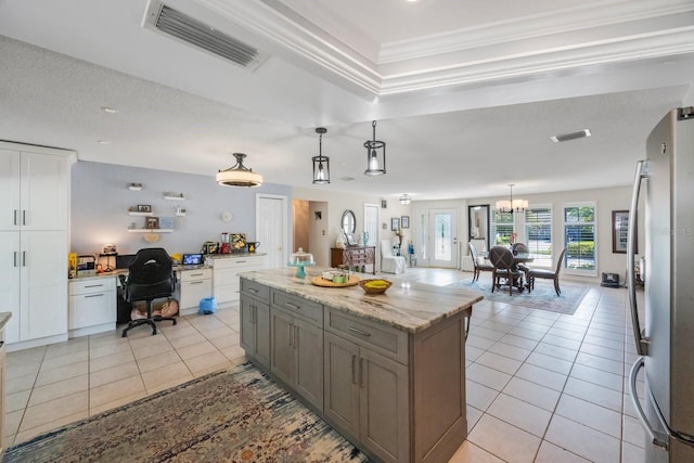 kitchen with stainless steel fridge, white cabinetry, light tile patterned flooring, pendant lighting, and crown molding