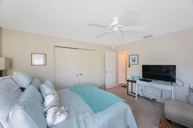 bedroom with a closet, ceiling fan, a textured ceiling, and light colored carpet