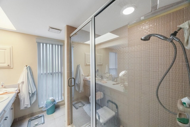 bathroom with a shower with door, vanity, and tile patterned floors