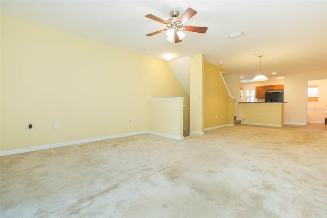 unfurnished living room featuring vaulted ceiling, ceiling fan, and light colored carpet