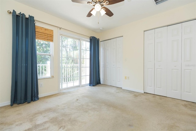 unfurnished bedroom featuring light carpet, multiple closets, ceiling fan, and access to exterior