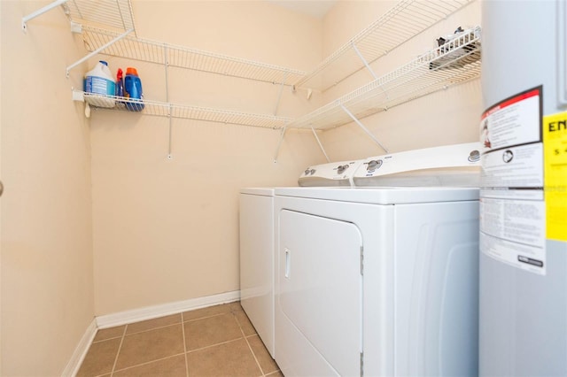 clothes washing area with washer and clothes dryer, water heater, and tile patterned floors