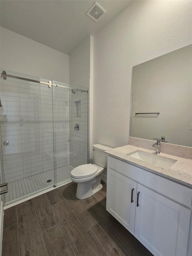 bathroom with vanity, toilet, wood-type flooring, and an enclosed shower