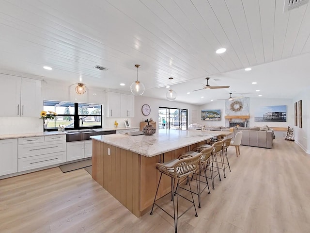 kitchen featuring a large island, light stone counters, and white cabinets