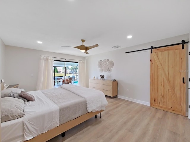 bedroom with ceiling fan, a barn door, access to exterior, and light hardwood / wood-style floors