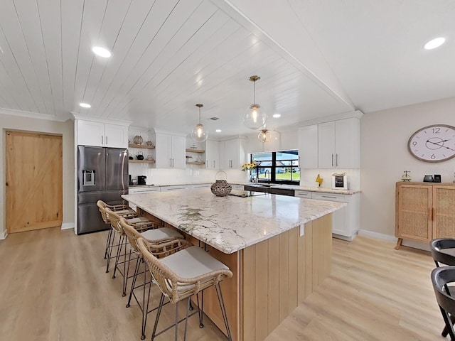 kitchen with a kitchen island, white cabinets, hanging light fixtures, stainless steel refrigerator with ice dispenser, and light hardwood / wood-style flooring