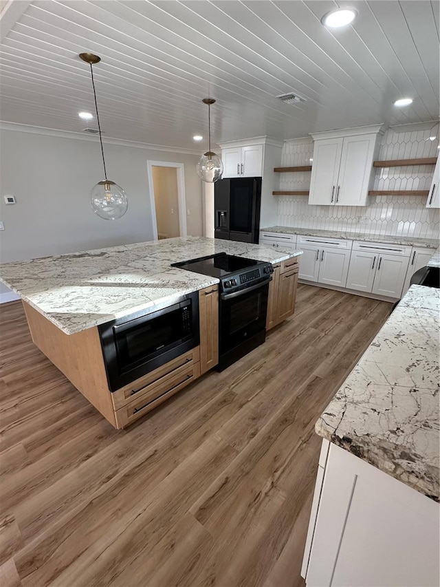 kitchen with black electric range oven, decorative light fixtures, white cabinets, and a kitchen island