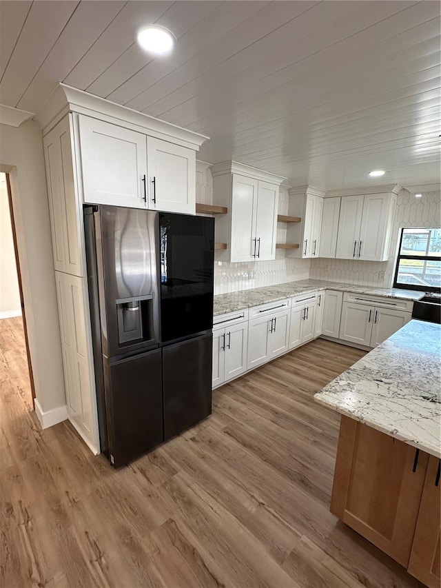 kitchen with white cabinetry, tasteful backsplash, light stone counters, stainless steel fridge with ice dispenser, and light wood-type flooring