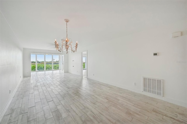 spare room with light hardwood / wood-style floors and an inviting chandelier