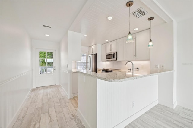 kitchen featuring stainless steel appliances, light wood-type flooring, kitchen peninsula, and white cabinetry