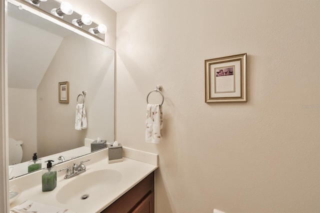 bathroom with vanity, lofted ceiling, and toilet