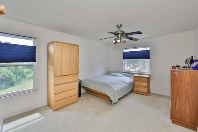 bedroom featuring multiple windows, light colored carpet, and ceiling fan