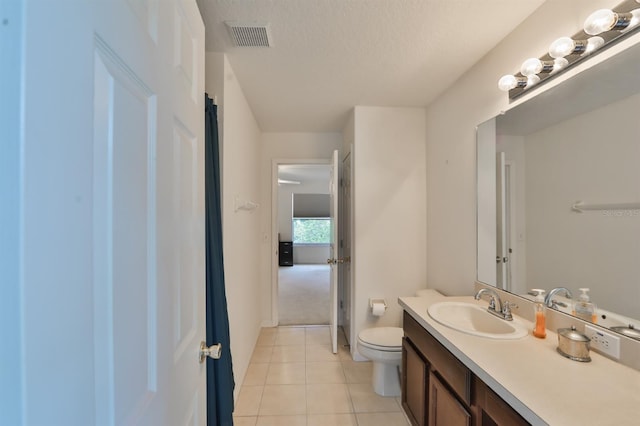 bathroom with vanity, a textured ceiling, toilet, and tile patterned flooring