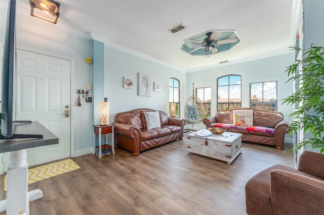 living room featuring wood-type flooring, ornamental molding, and ceiling fan