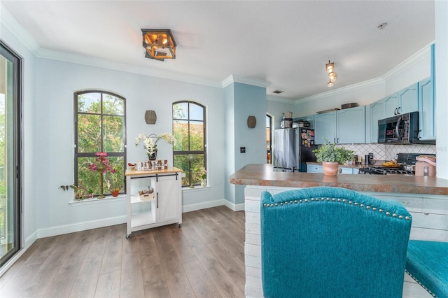 kitchen featuring range, light hardwood / wood-style flooring, ornamental molding, blue cabinets, and stainless steel fridge