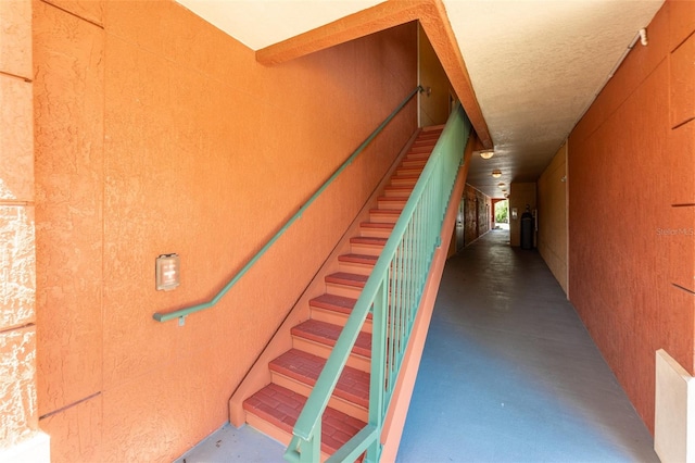 staircase with concrete flooring and wooden walls