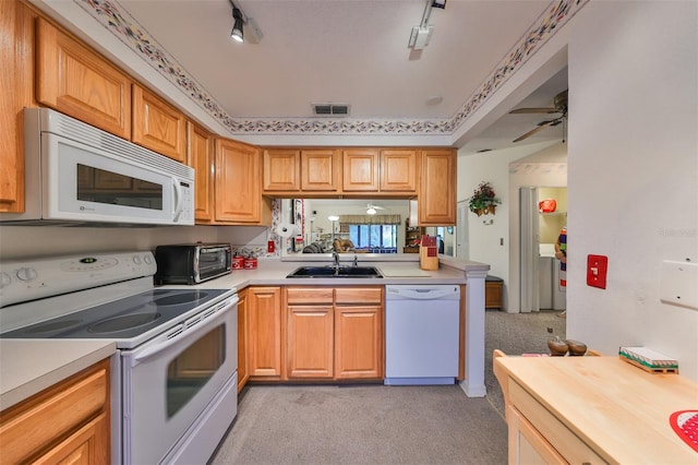 kitchen with white appliances, light carpet, track lighting, and sink