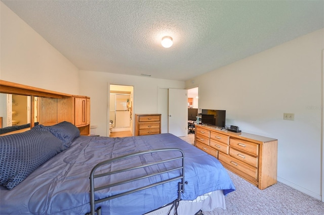 bedroom with a textured ceiling, connected bathroom, and light colored carpet