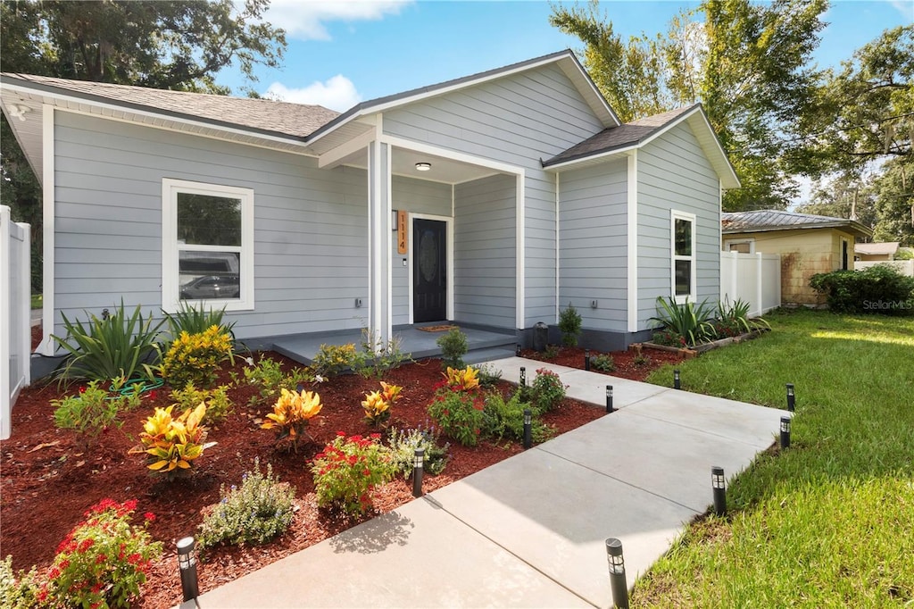 single story home featuring a front yard, covered porch, and fence