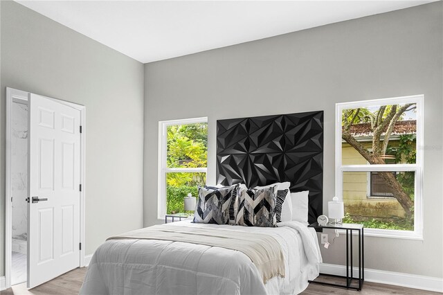 bedroom with multiple windows and hardwood / wood-style flooring