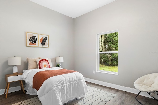 bedroom with multiple windows and dark hardwood / wood-style floors