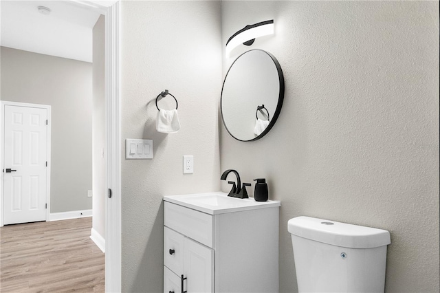 bathroom featuring wood-type flooring, vanity, and toilet