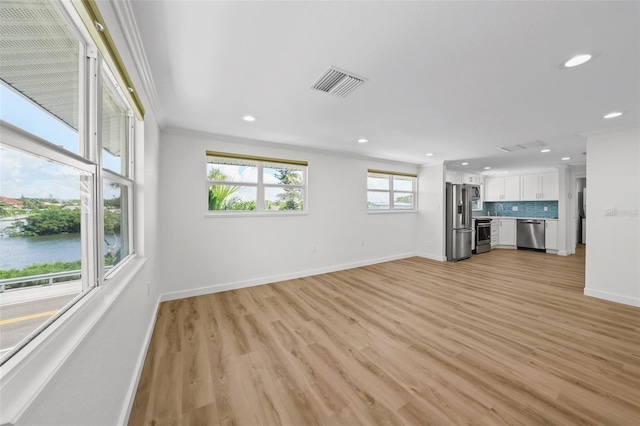 unfurnished living room featuring a water view, sink, light hardwood / wood-style floors, and crown molding