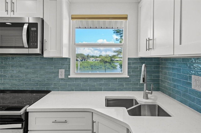 kitchen featuring sink, white cabinetry, range, and decorative backsplash