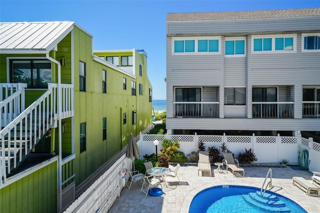 back of house with a fenced in pool, a patio area, and a water view