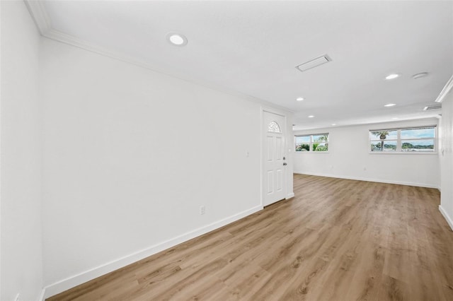 spare room featuring crown molding and light hardwood / wood-style flooring