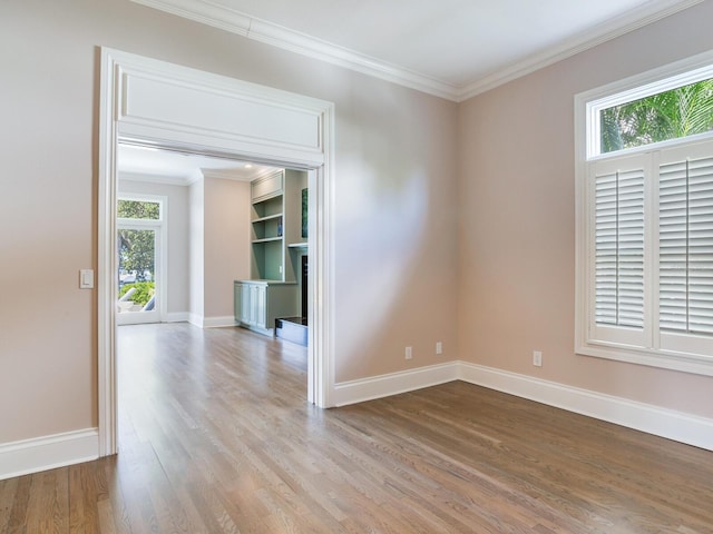 empty room featuring light hardwood / wood-style floors, crown molding, and a wealth of natural light