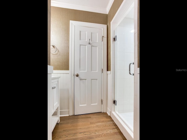 bathroom featuring a shower with door, ornamental molding, vanity, and wood-type flooring