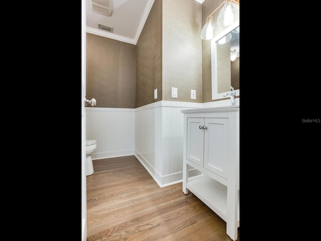 bathroom featuring vanity, hardwood / wood-style floors, crown molding, and toilet