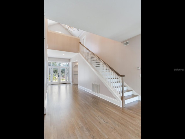 living room with lofted ceiling, french doors, and light wood-type flooring