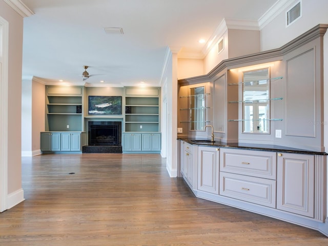 kitchen featuring ceiling fan, ornamental molding, a fireplace, light hardwood / wood-style floors, and sink