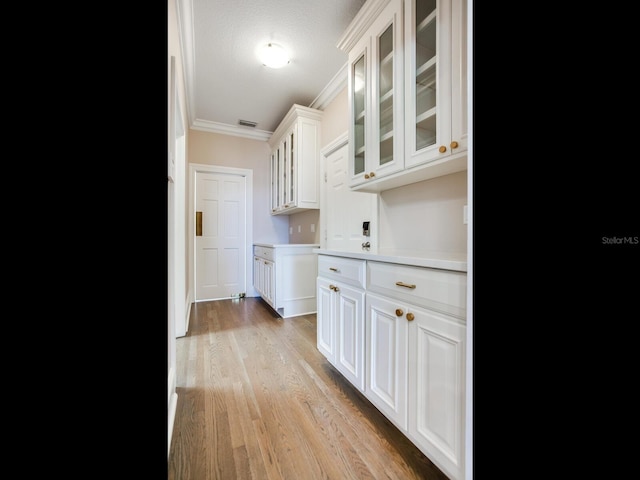 kitchen featuring ornamental molding, light hardwood / wood-style flooring, and white cabinets