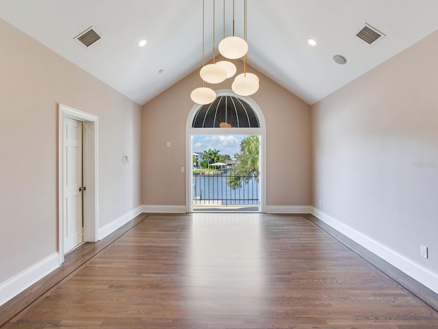 empty room with high vaulted ceiling and wood-type flooring