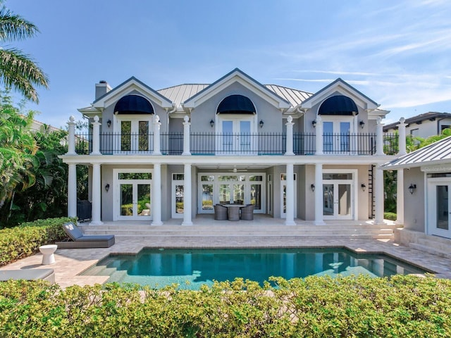 back of property with a patio, french doors, and a balcony