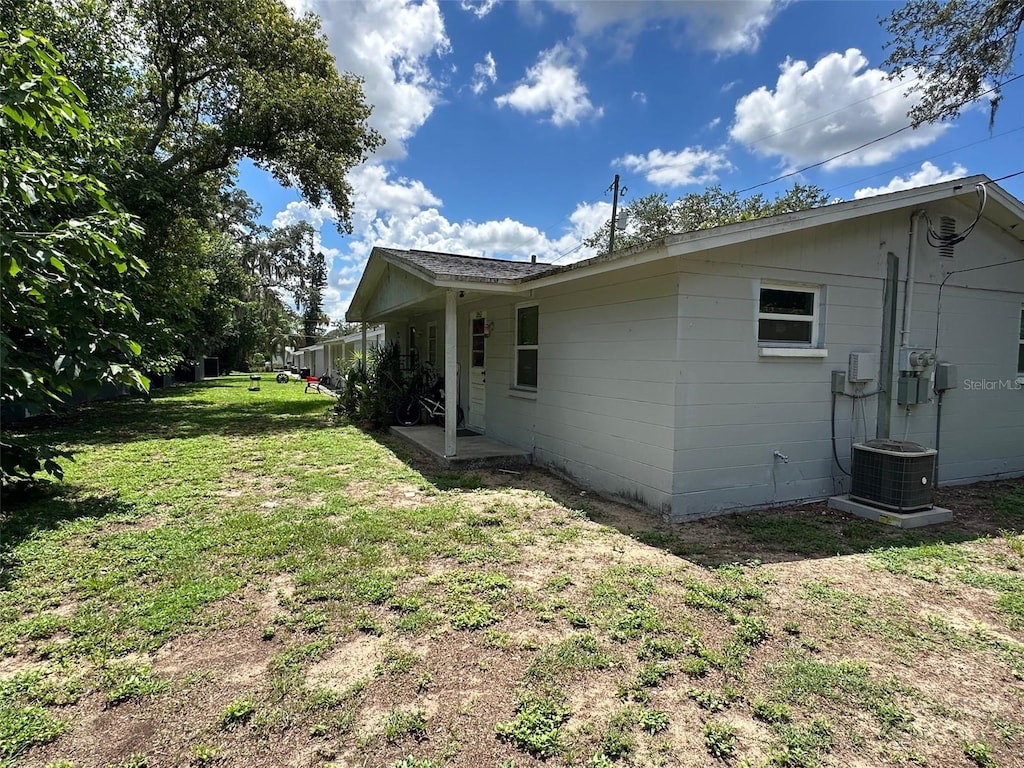 view of side of home with a lawn and central AC