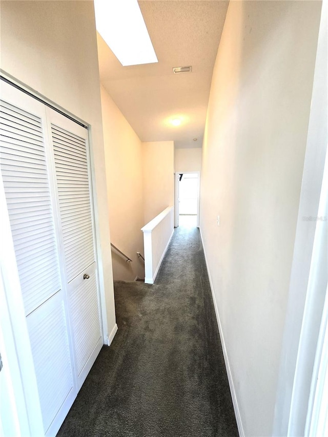 corridor featuring dark colored carpet and a skylight