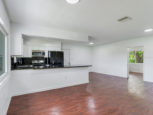 kitchen featuring dark hardwood / wood-style floors, sink, white cabinets, kitchen peninsula, and stainless steel appliances