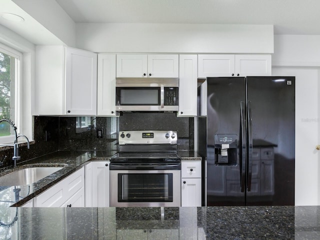 kitchen with appliances with stainless steel finishes, backsplash, dark stone countertops, and white cabinets