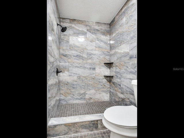 bathroom featuring a textured ceiling, tiled shower, toilet, and tile patterned flooring